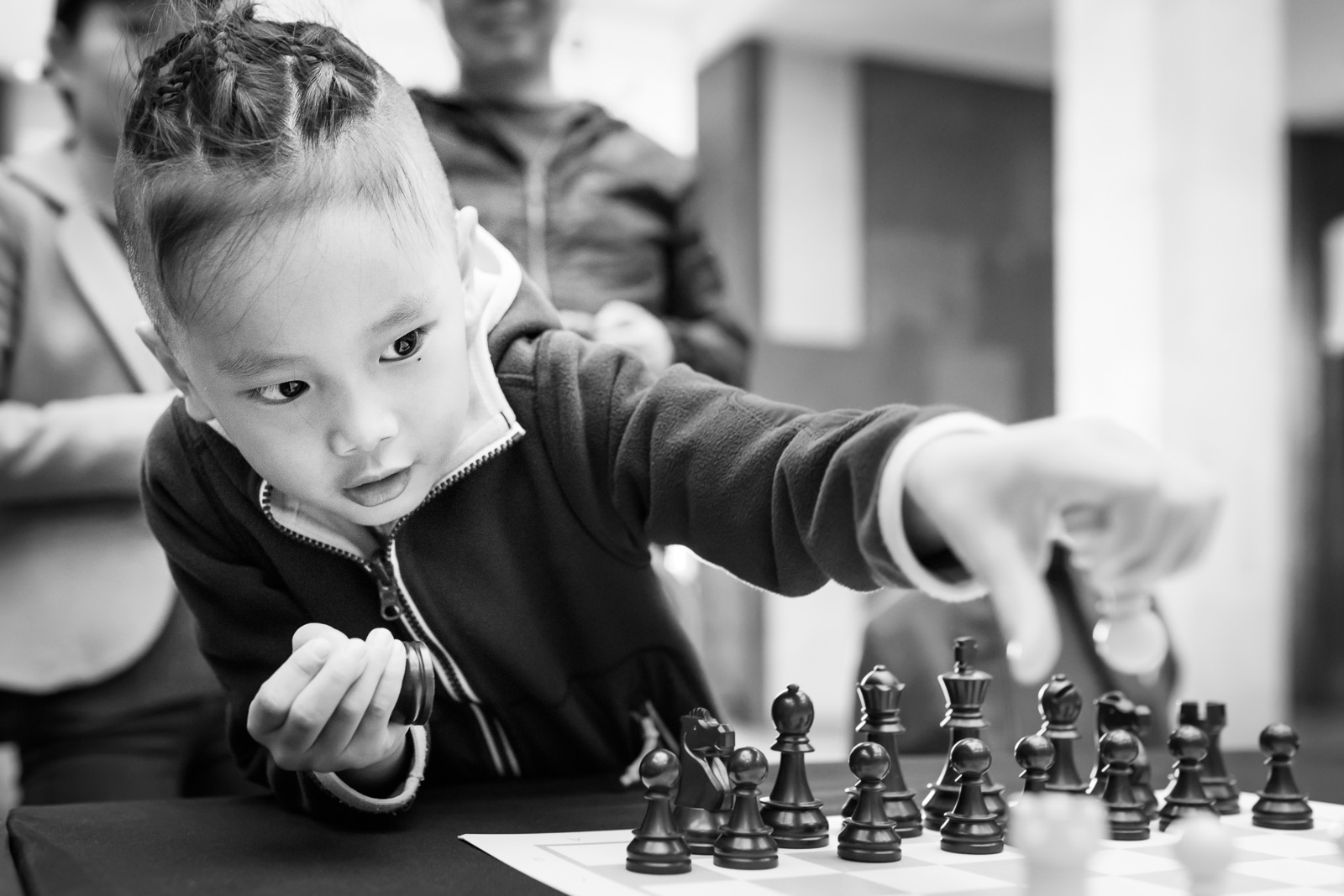 girl reaches across chess board